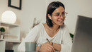 Das Foto zeigt eine Frau, die im Homeoffice ist und gerade an einer Videokonferenz teilnimmt.
