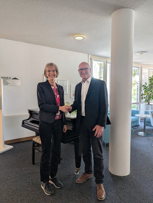 Eine Frau und ein Mann schütteln sich in einem Büro die Hand