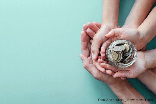 Ein Kind und Erwachsene halten ein Glas mit Geld
