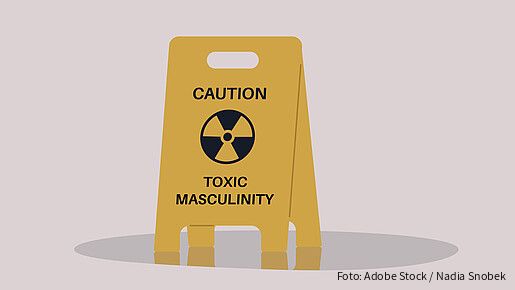 A yellow floor sign warning about toxic masculinity, the idea of manliness as being defined by domination, homophobia, and aggression