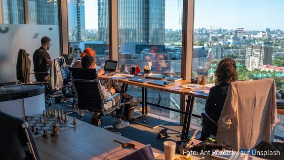 Menschen an einem modernen Arbeitsplatz vor Laptops