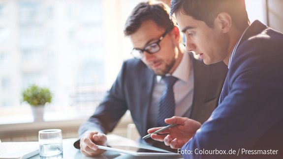 Digitalisierung Zwei Männer im Büro sehen gemeinsam auf Tablet und besprechen sich
