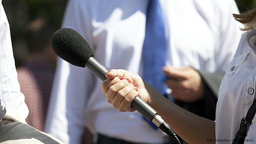 Eine Frau hält einer anderen Person ein Mikrofon hin