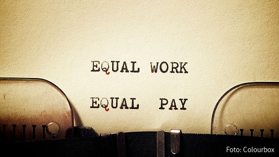 Auf einem in eine Schreibmaschine eingespannten Blatt stehen die getippten Worte "Equal Work - Equal Pay"