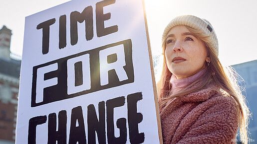 Eine junge Frau hält bei einer Demonstration ein Plakat mit der Aufschrift "Time for Change" hoch.