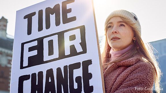 Eine junge Frau hält bei einer Demonstration ein Plakat mit der Aufschrift "Time for Change" hoch.