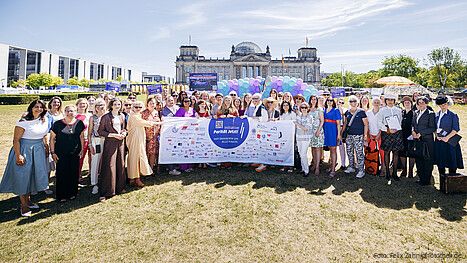 Gruppenfoto von Menschen in formaler Kleidung vor dem Bundestag