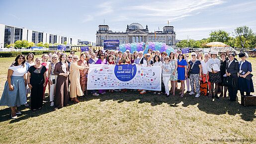 Gruppenfoto von Menschen in formaler Kleidung vor dem Bundestag