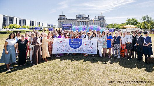 Gruppenfoto von Menschen in formaler Kleidung vor dem Bundestag