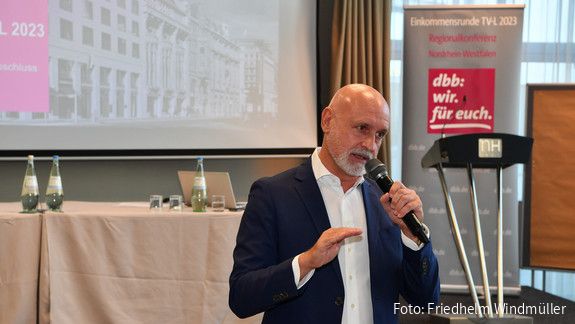 Regionalkonferenz in Düsseldorf Ein Mann steht vor einer Leinwand mit einem Mikrofon in der Hand