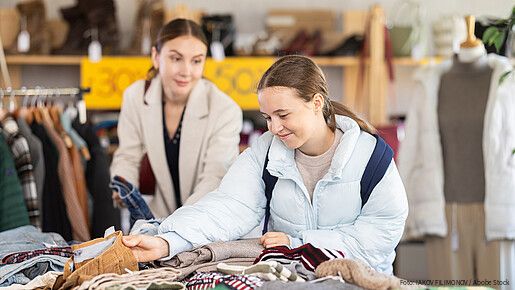 Woman with a teenage daughter chooses woolen warm pants near the counter in the sale area. Family shopping for winter clothes in the store