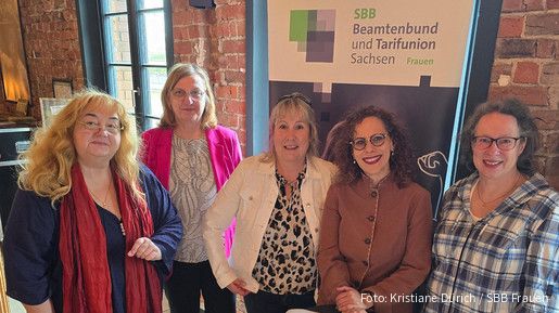 Fünf Frauen stehen vor einer Backsteinwand und blicken in die Kamera