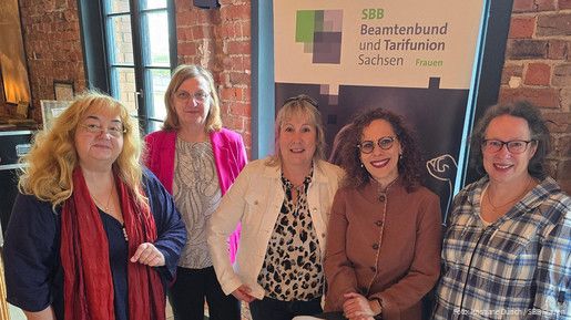 Fünf Frauen stehen vor einer Backsteinwand und blicken in die Kamera