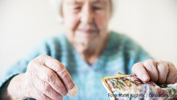 Eine unglücklich wirkende Seniorin zählt am Tisch die wenigen Münzen ihre Pension.