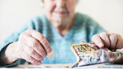 Eine unglücklich wirkende Seniorin zählt am Tisch die wenigen Münzen ihre Pension.