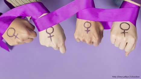 Vier Frauenhände mit einem aufgemalten Frauen-Symbol, ein violettes Band ist um die Handgelenke gelegt
