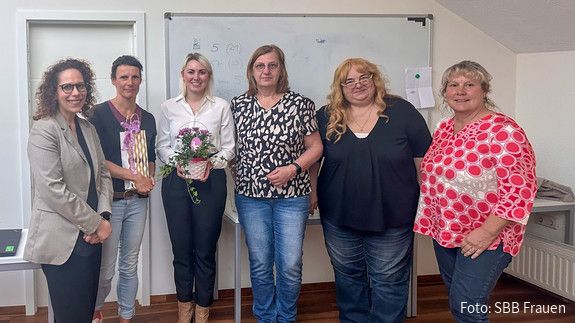 Eine Gruppe Frauen steht vor einem Whiteboard und blicken in Richtung Kamera