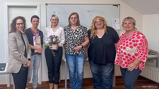 Eine Gruppe Frauen steht vor einem Whiteboard und blicken in Richtung Kamera