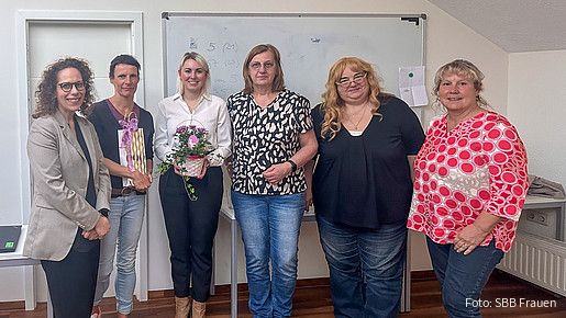 Eine Gruppe Frauen steht vor einem Whiteboard und blicken in Richtung Kamera