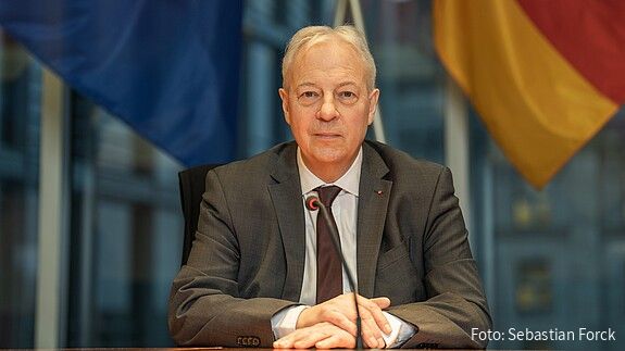 Markus Töns sitzt vor der deutschen und europäischen Flagge