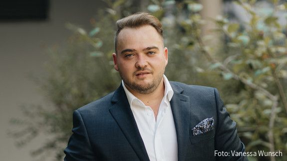 dbb jugend zum Tag der Deutschen Einheit Matthäus Fandrejewski, Vorsitzender der dbb jugend, steht in einem begrünten Innenhof.