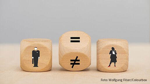 Zu sehen sind drei Würfel: Einer mit einer männlichen Figur, einer mit einer weiblichen. Der Würfel in der Mitte steht gekippt, ein Gleichheitszeichen und ein Ungleichheitszeichen sind zu sehen.