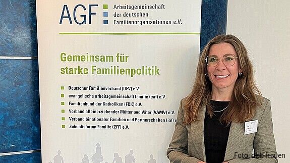 Eine Frau steht vor einem bunten Aufsteller
