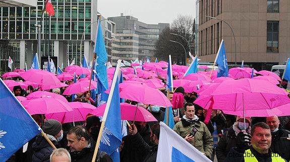 Es ist ein Demozug zu sehen, auf dem viele pinke Regenschirme gespannt wurden.