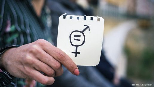 Frau hält Zettel mit Gleichheitssymbol (Symbolbild)