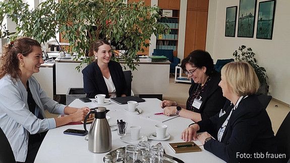 Drei Frauen sitzen an einem Tisch und diskutieren
